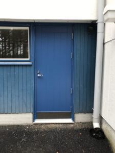 sininen umpinainen ulko-ovi pystyura kuviolla ja potkulevyllä