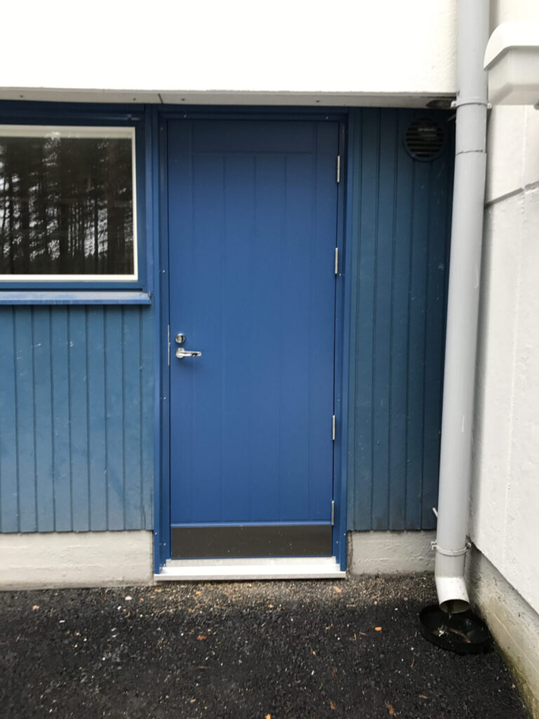 sininen umpinainen ulko-ovi pystyura kuviolla ja potkulevyllä